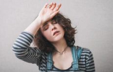 Woman pressing the back of her hand to her forehead, flushed and uncomfortable